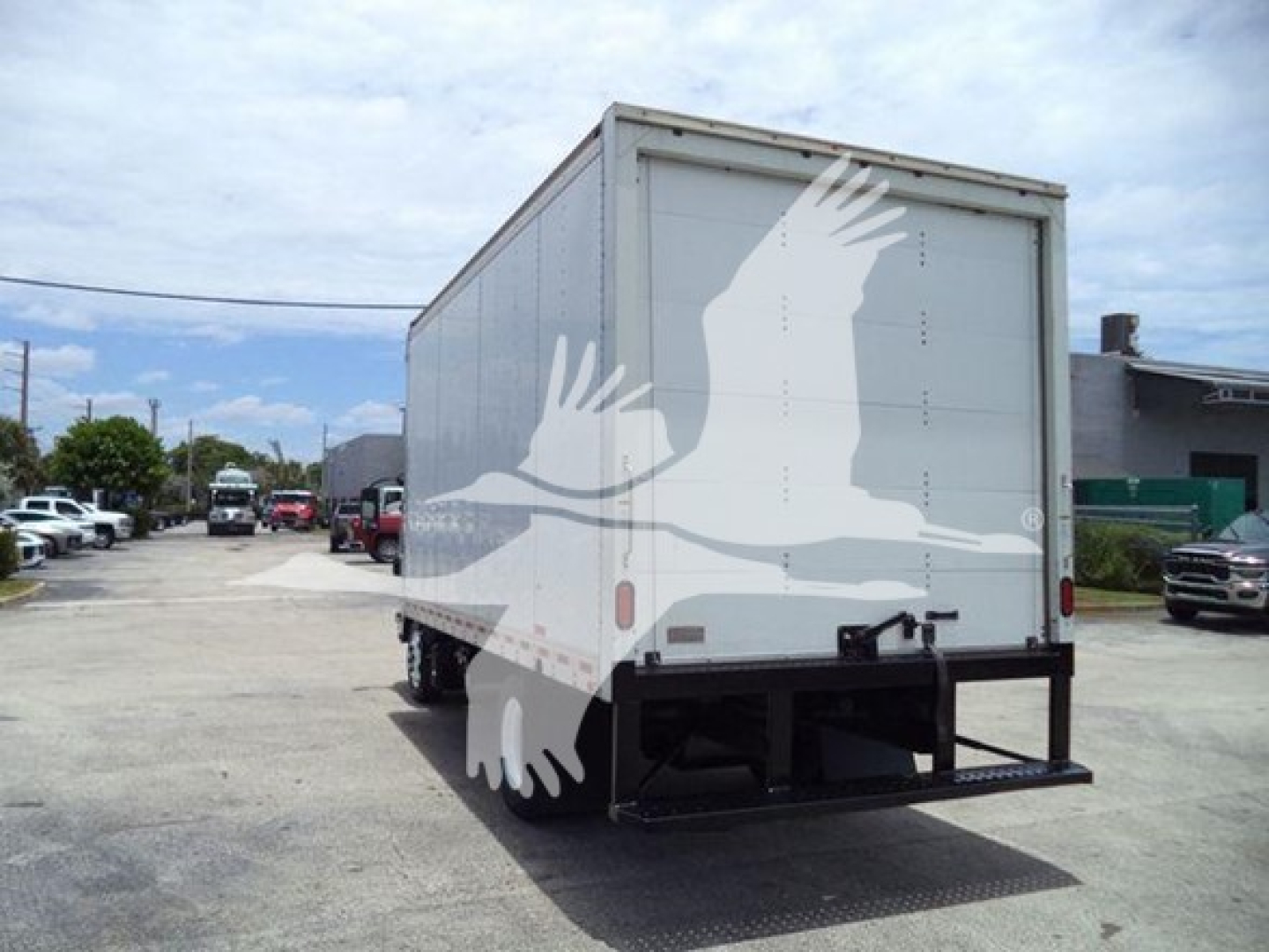 Isuzu NRR box truck rear view showing cargo box and ramp/bumper with white bird graphic on side