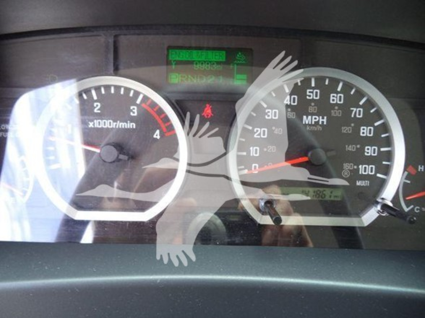Isuzu NPR/NRR gauge cluster showing tachometer and speedometer with green digital readout above; odometer and dashboard in view.