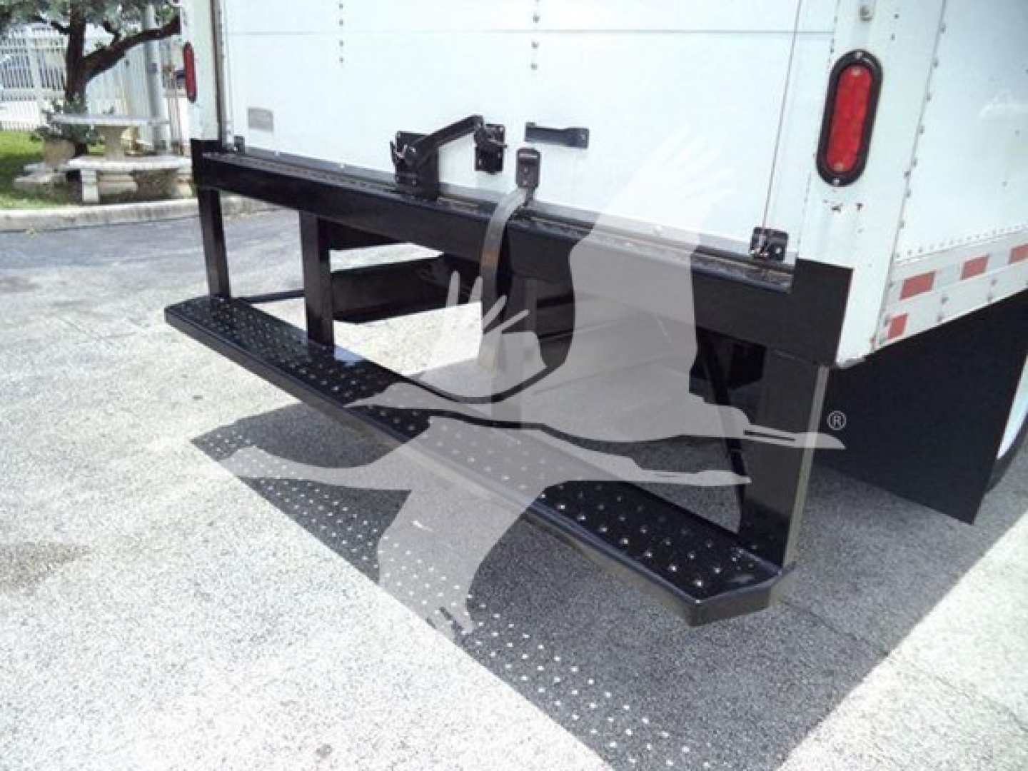 Isuzu NRR rear/side view showing heavy-duty fold-out cargo step/bumper with textured stepping surface and black metal platform.