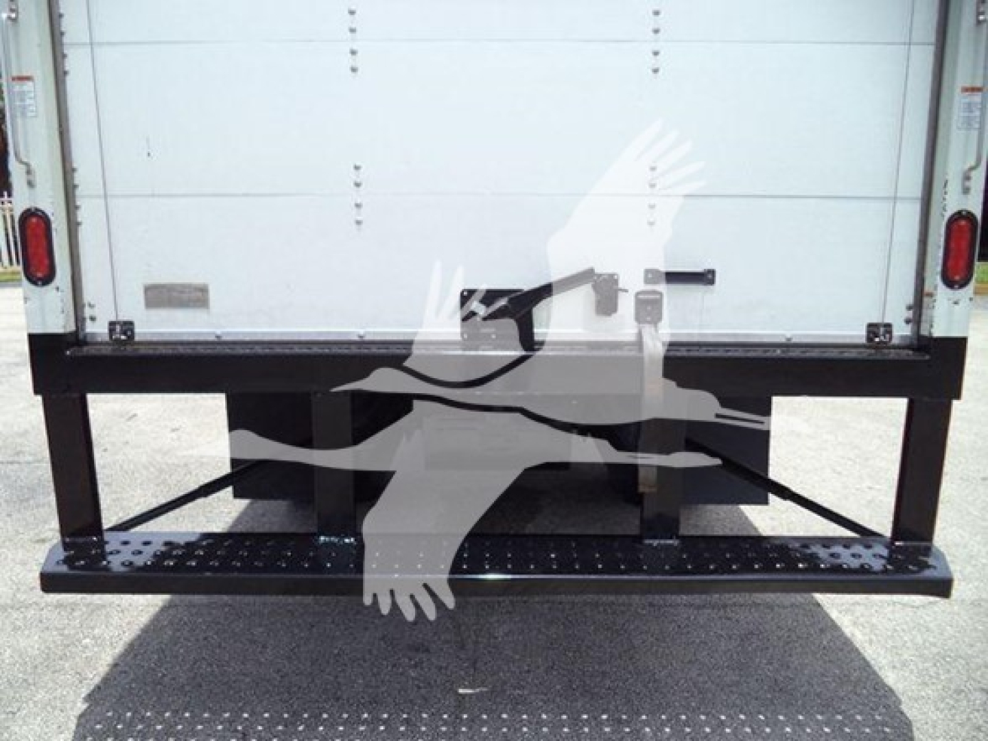 Isuzu NRR truck rear view showing a black steel lift/step bumper with steps, and white box van body in background.