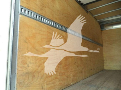 Isuzu box truck interior showing wooden cargo area with metal rails and a graphic of flying geese on the wall.