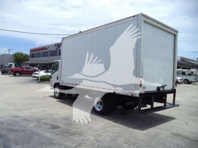 Isuzu NRR box truck rear and side view showing cargo box with white graphics and metal frame, rear bumper, and truck cab in distance.