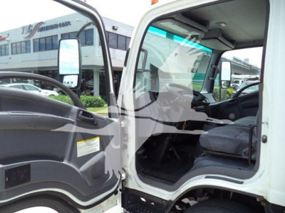 Isuzu NRR truck cab interior and open door showing steering wheel and driver seat with dashboard, exterior side mirror, and view of box truck in background.