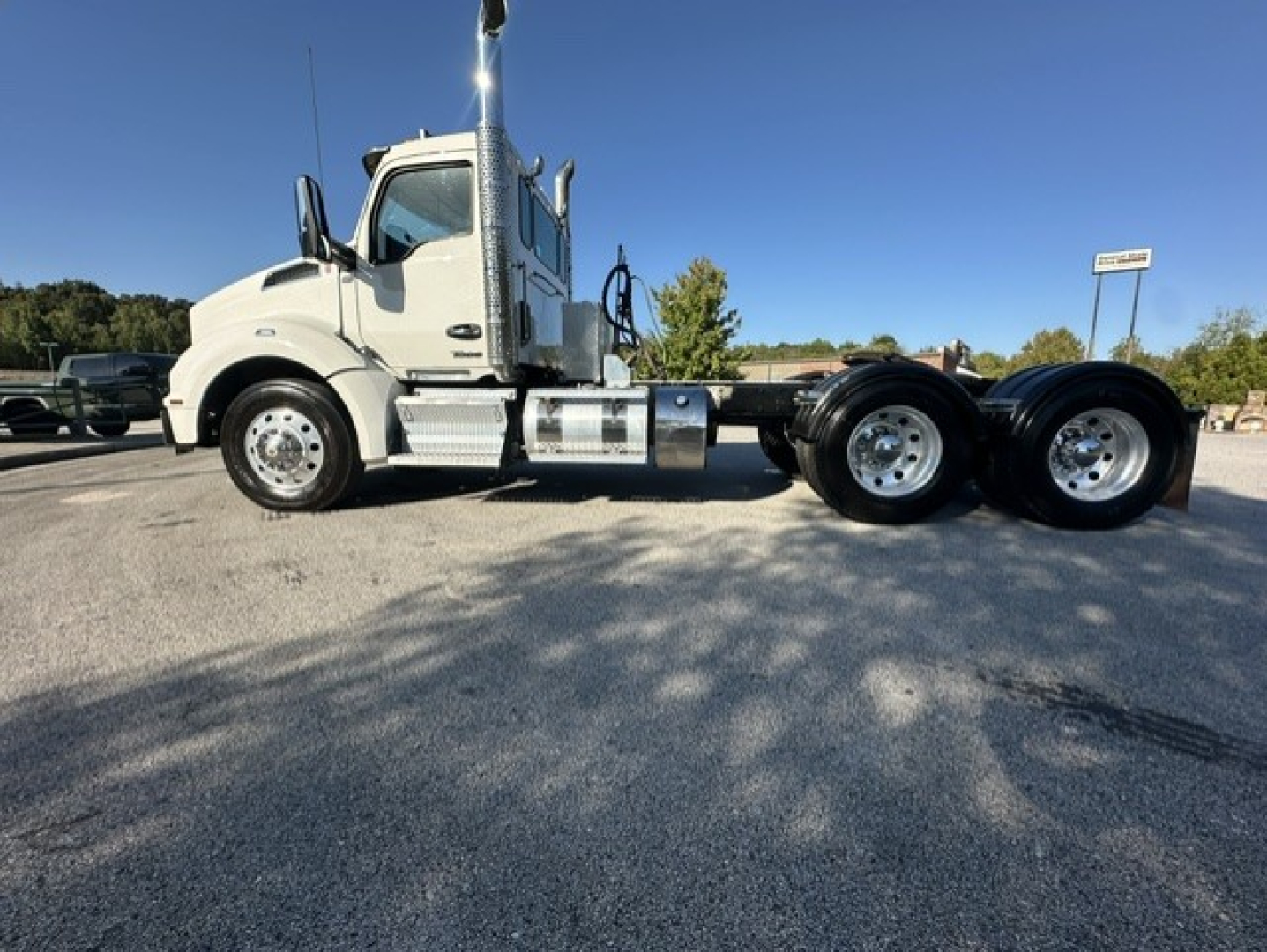 Kenworth T880 daycab truck side view showing dual rear axles and chrome fuel tanks