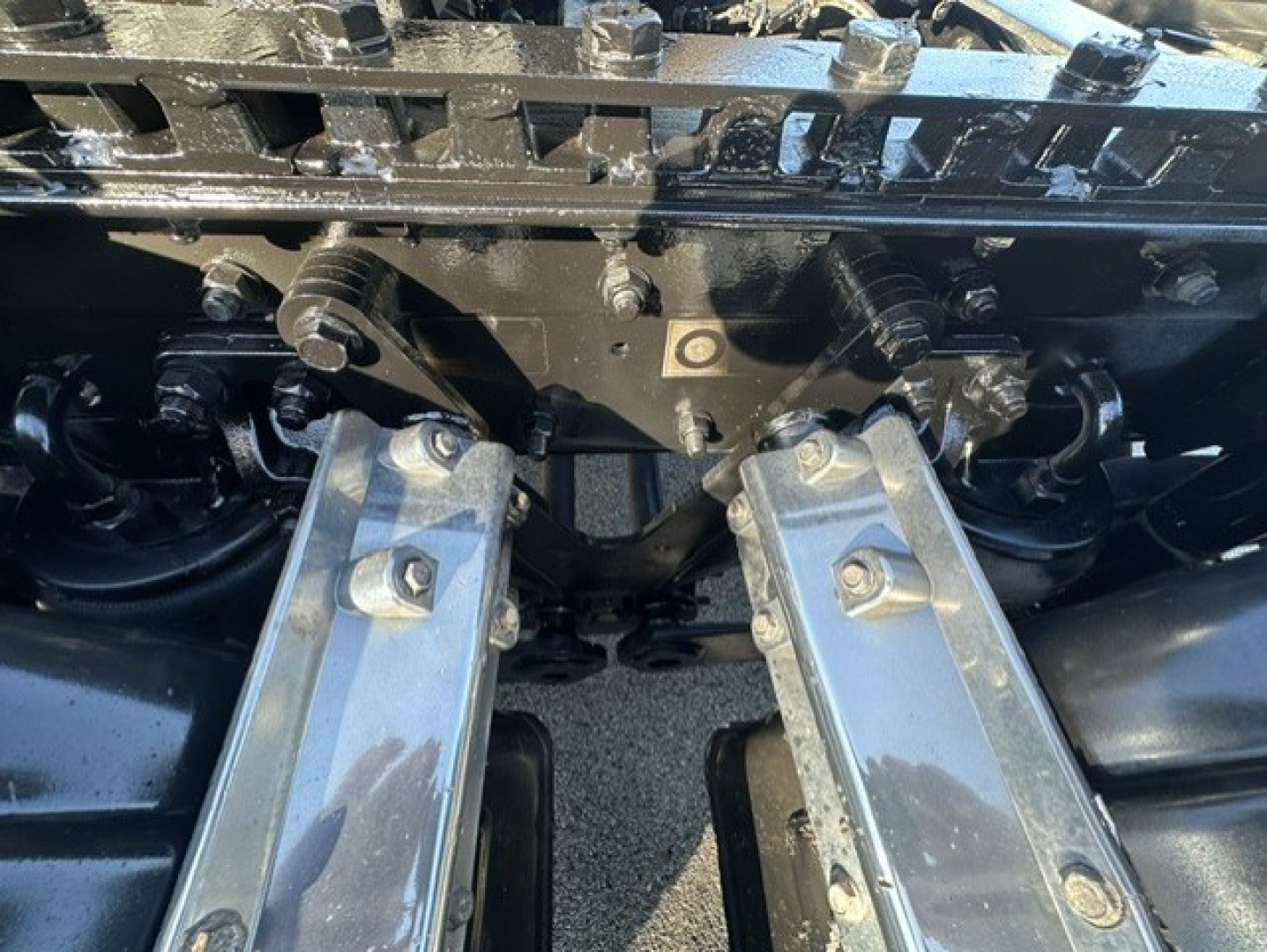 Front view of a 2025 Kenworth T880 conventional daycab chassis showing the underbelly and mounting hardware with chrome rails and suspension components.