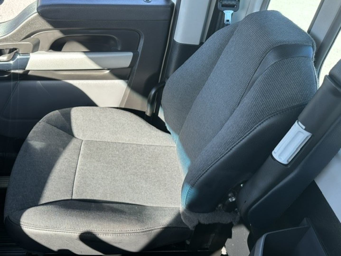 Cab interior of a 2025 Kenworth T880 truck showing front gray fabric seat and part of the door panel.