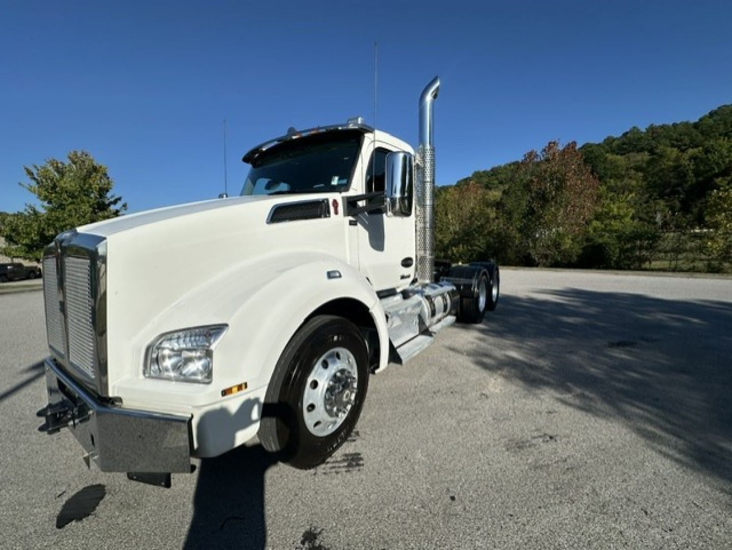 Kenworth T880 conventionals daycab side/front view showing chrome exhaust stack and white cab.