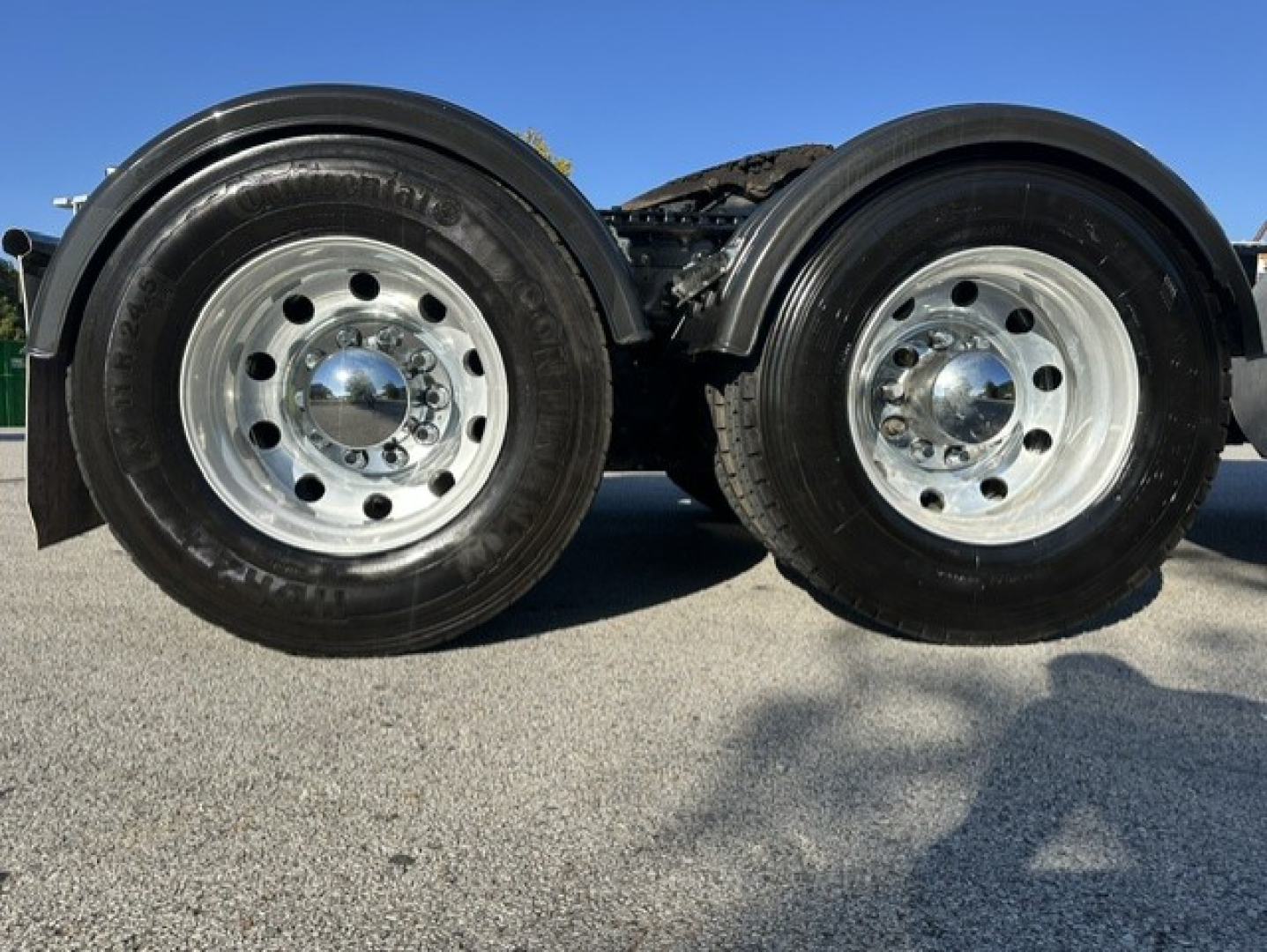 Kenworth T880 tandem axle wheels and tires viewed low angle showing chrome hubcaps and dual wheels.