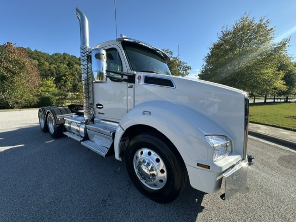 Kenworth T880 conventional daycab truck in white, side view showing chrome exhaust stack, dual rear axles, and polished wheels.