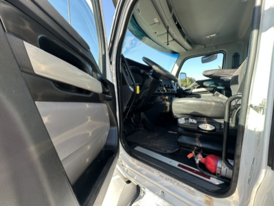 Truck cab interior showing steering wheel, driver seat, dashboard, and entry step with door panel in view.