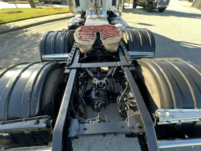 Kenworth T880 chassis rear view showing fifth wheel, dual rear axles, and drive line components.