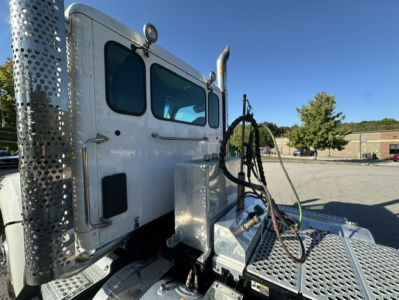 Kenworth T880 conventional daycab truck side view showing driver cab and chrome exhaust stacks with perforated heat shields and crew access area.