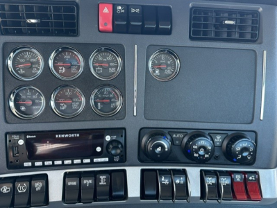 Kenworth T880 dash panel showing multiple gauges and Kenworth radio, air controls, and switches.