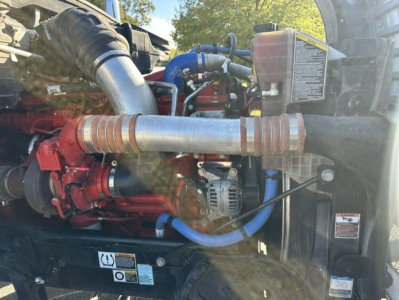 Kenworth T880 engine bay showing air intake, turbo, hoses, and coolant reservoir with labeled decals.