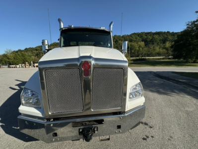 Kenworth T880 conventional daycab front view showing large chrome grille with mesh inserts, dual headlights, bumper with hitch, and badges on the hood.