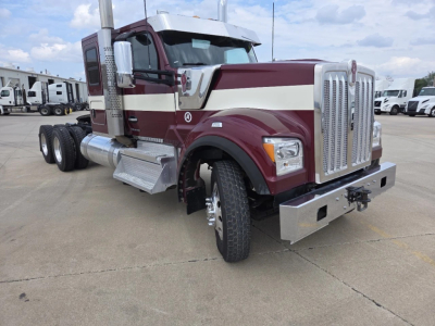 Kenworth W990 conventional sleeper truck with maroon and cream paint, chrome grille, and dual rear axles; front bumper and side steps visible.