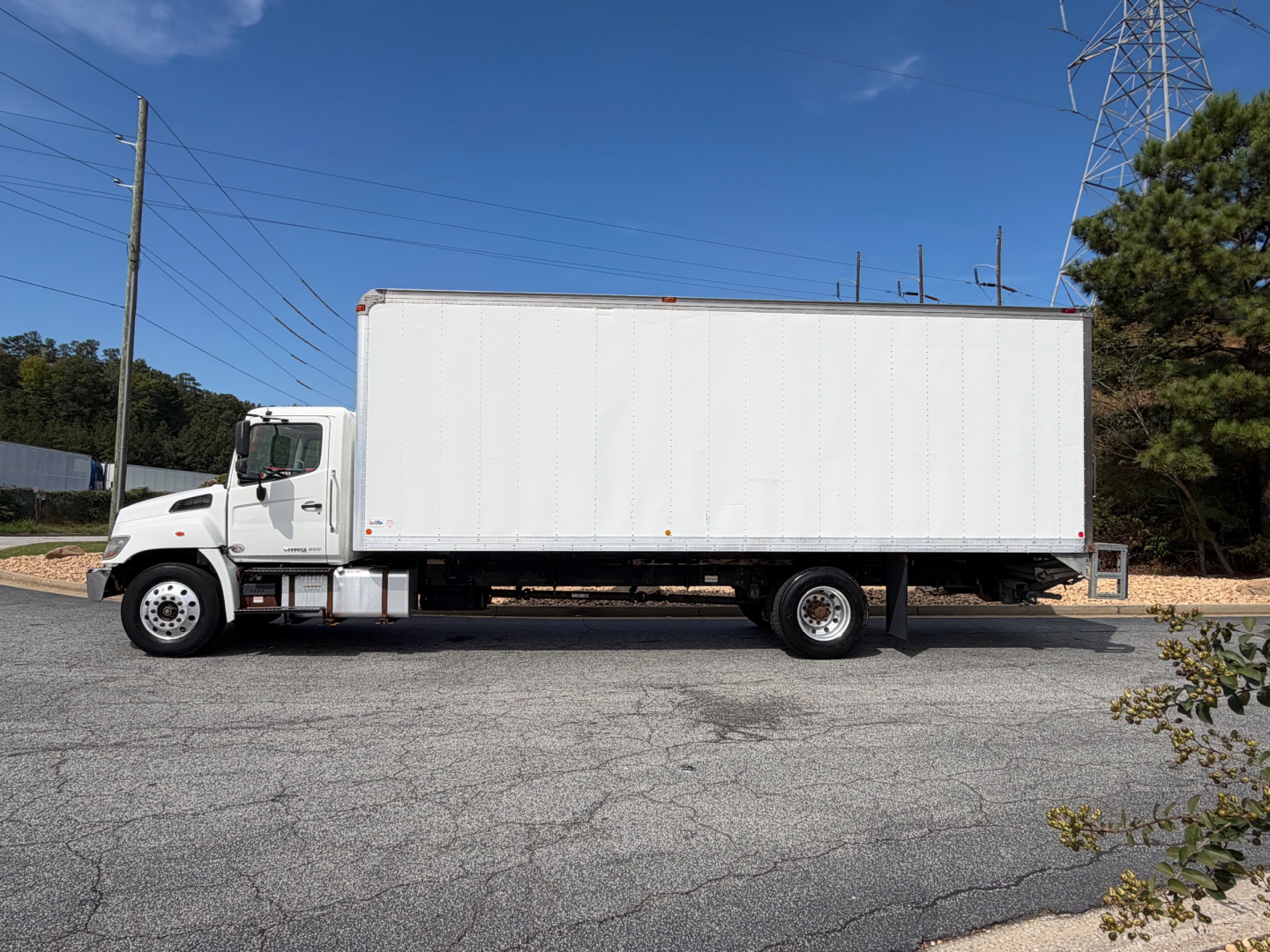White box truck with cab in foreground, side view showing cargo area and wheels.
