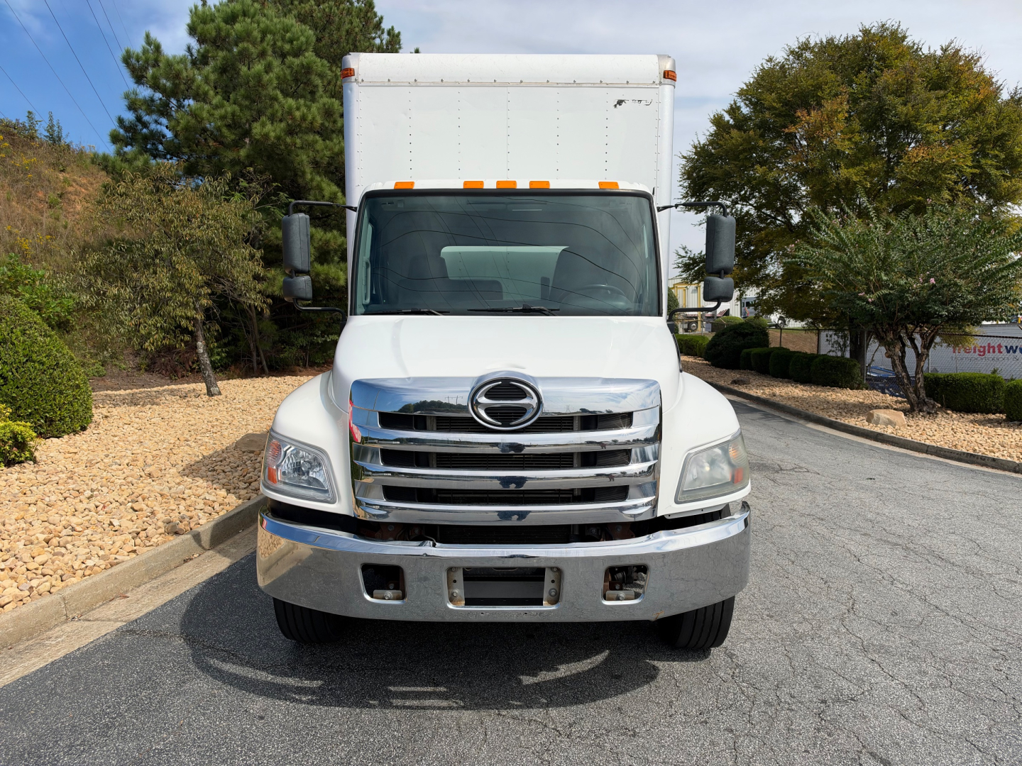 Front view of a white 2019 Hino 268A box truck showing chrome grille, large bumper, and side mirrors.