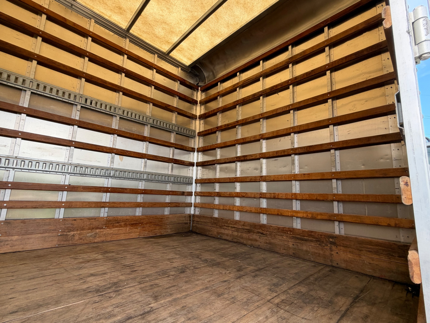 Hino 268A box truck interior showing wooden side rails and metal lining with plywood floor.