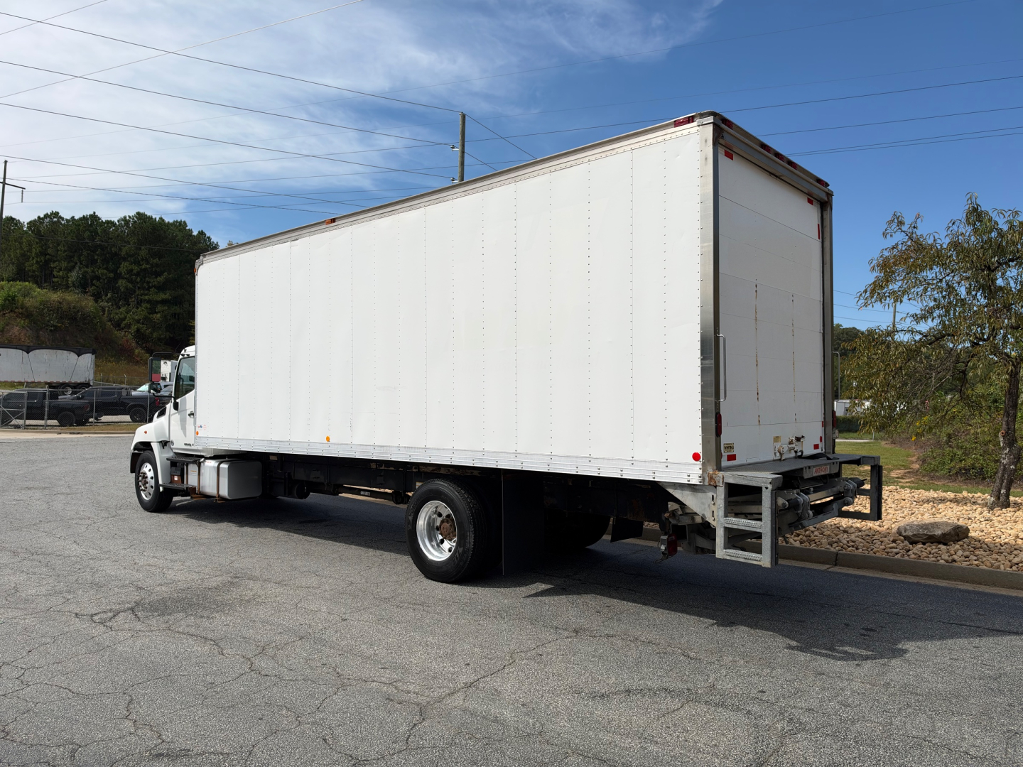 Box truck 2019 Hino 268A side/rear view showing large white box body and rear loading ramp.