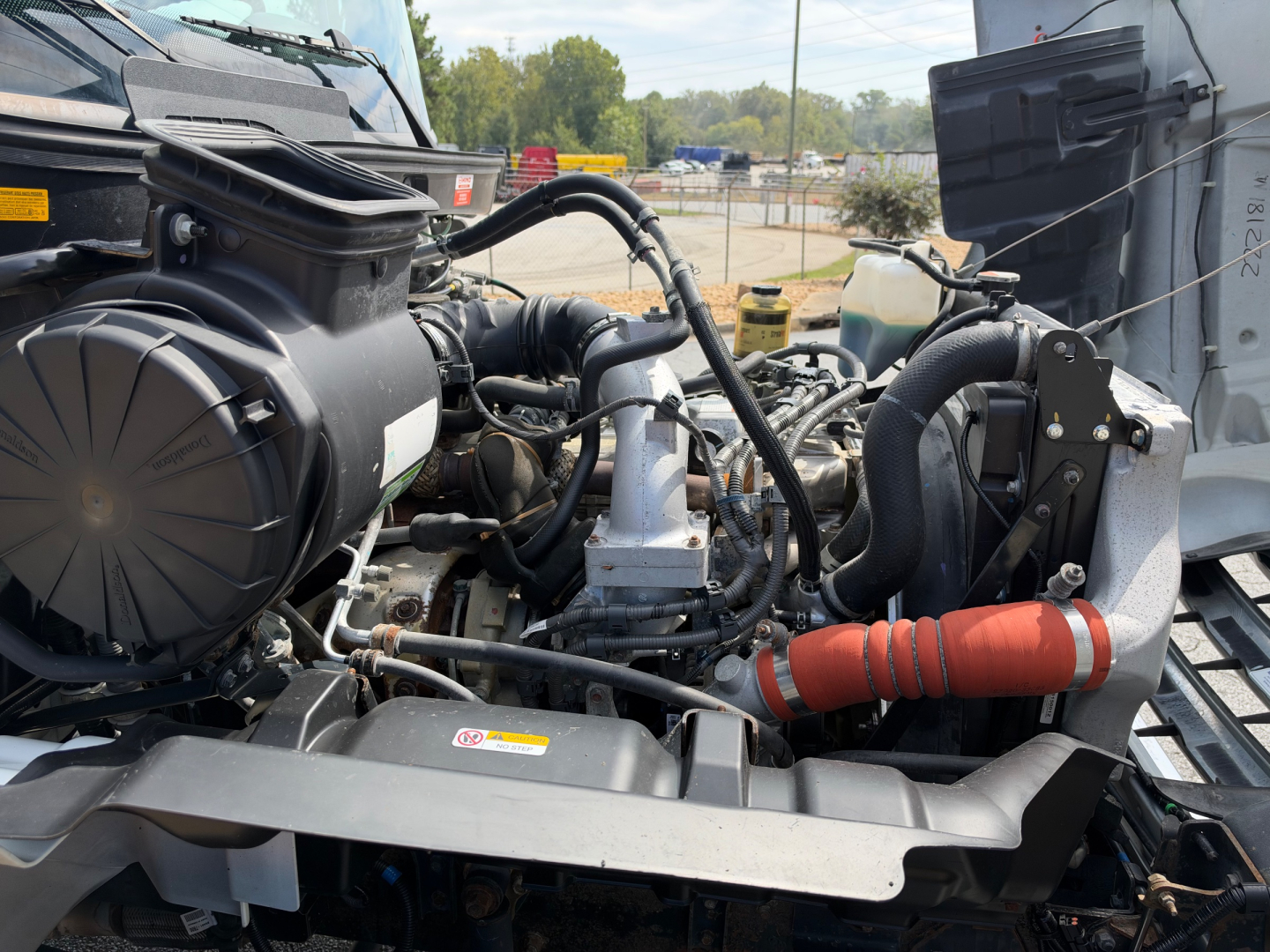 Hino 268A engine bay showing various hoses, air intake, and radiator area.