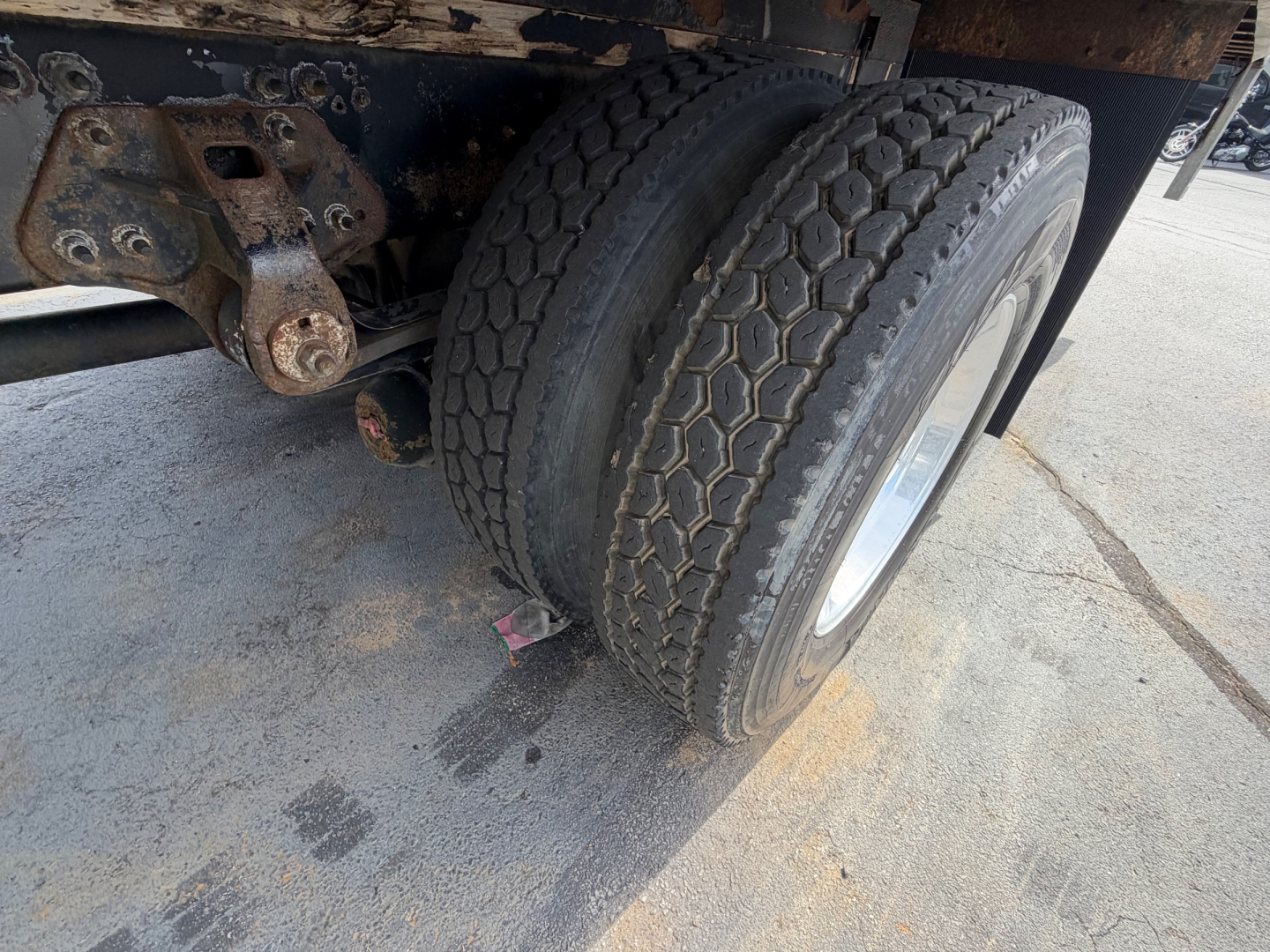 Hino 268A truck rear dual wheels showing chassis suspension, wheel rims, and tires with tread pattern; rust and dirt on frame components visible.