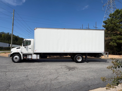 White box truck with cab in foreground, side view showing cargo area and wheels.
