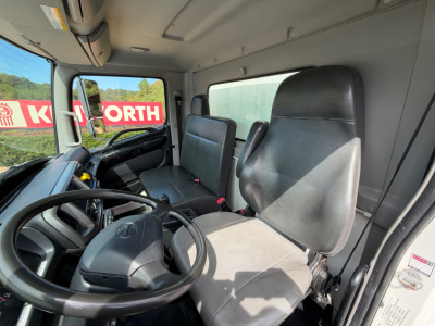Cab interior of a 2019 Hino 268A box truck showing steering wheel, driver seat, and passenger seat with dashboard visible.
