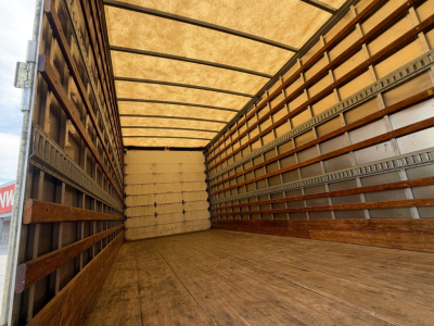 Truck trailer interior showing empty box with wooden floor and side rails.