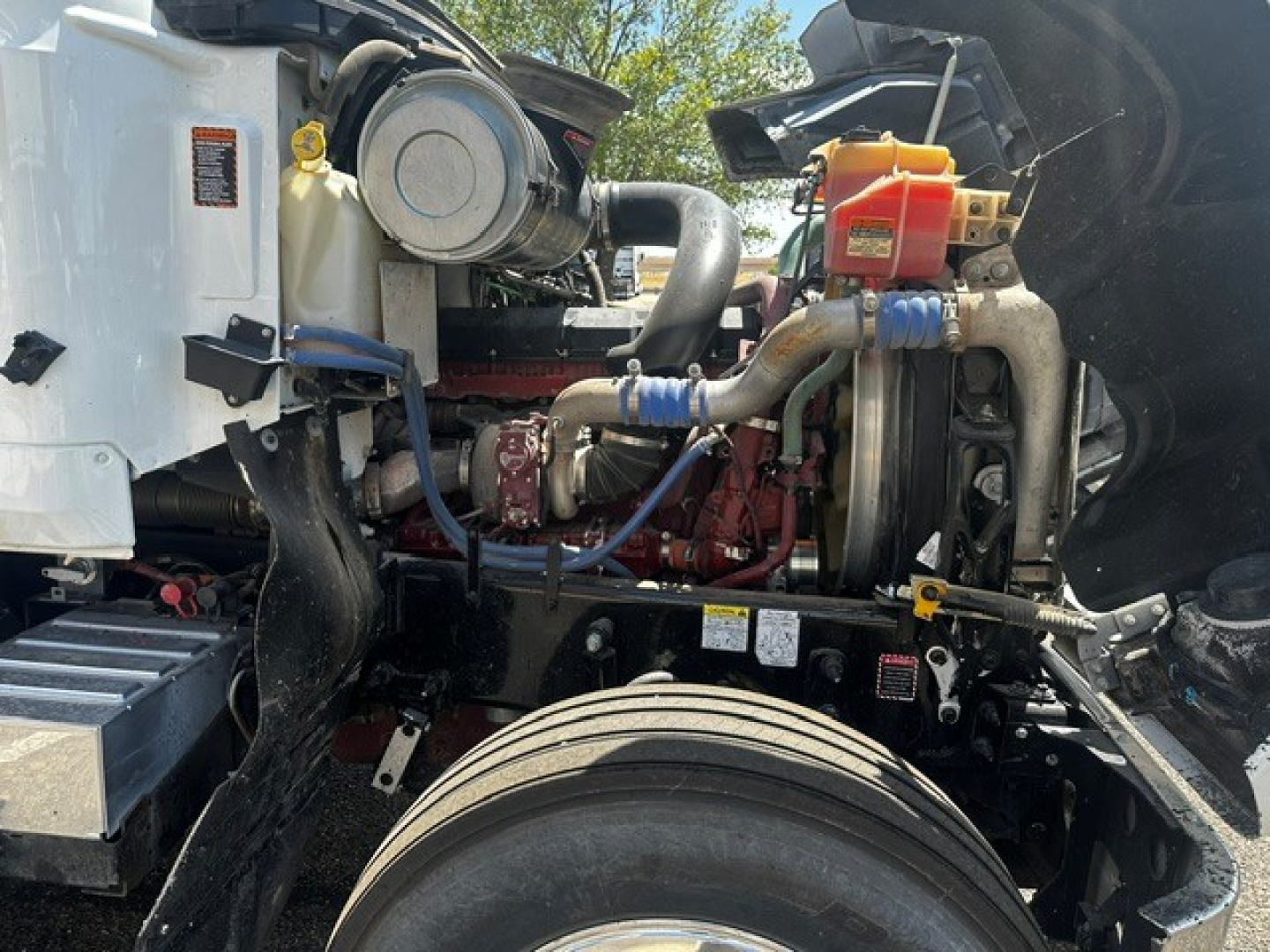 Engine bay of a 2022 Mack PI64T daycab showing engine components, hoses, and coolant reservoir and turbocharger.