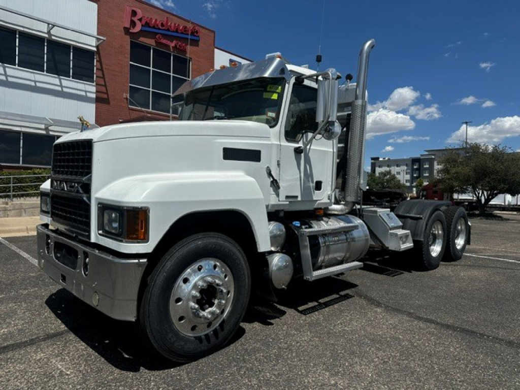 Mack PI64T conventional daycab truck in white, front-left angle, with chrome bumper, large fuel tanks, and dual rear axles.