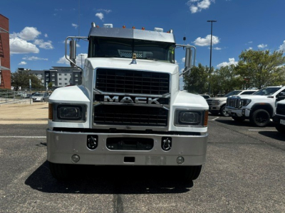 Mack PI64T conventional daycab truck front view showing large black grille with MACK lettering, square headlights, chrome bumper, two circular fog lights, and inspection/brand plates on hood.