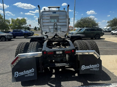 Truck rear view showing fifth wheel and dual rear tires on a Mack PI64T, with mud flaps labeled Bruchner's Truck & Equipment, tail lights, and chrome exhaust stacks.