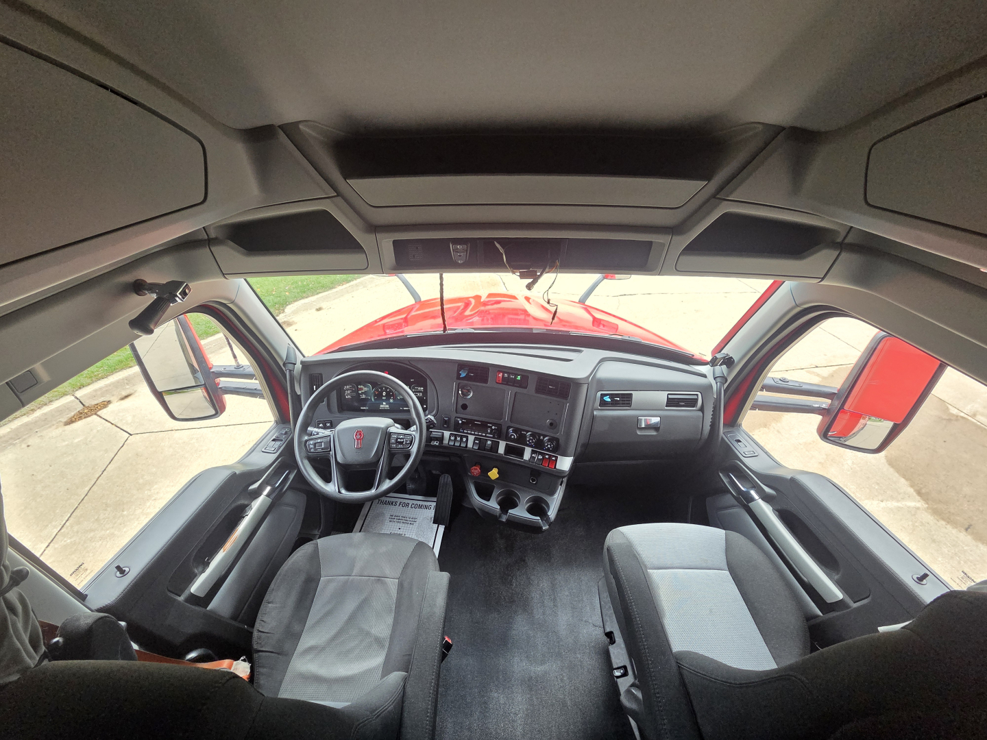 Kenworth T680 cab interior view with dashboard, steering wheel, and seats visible.