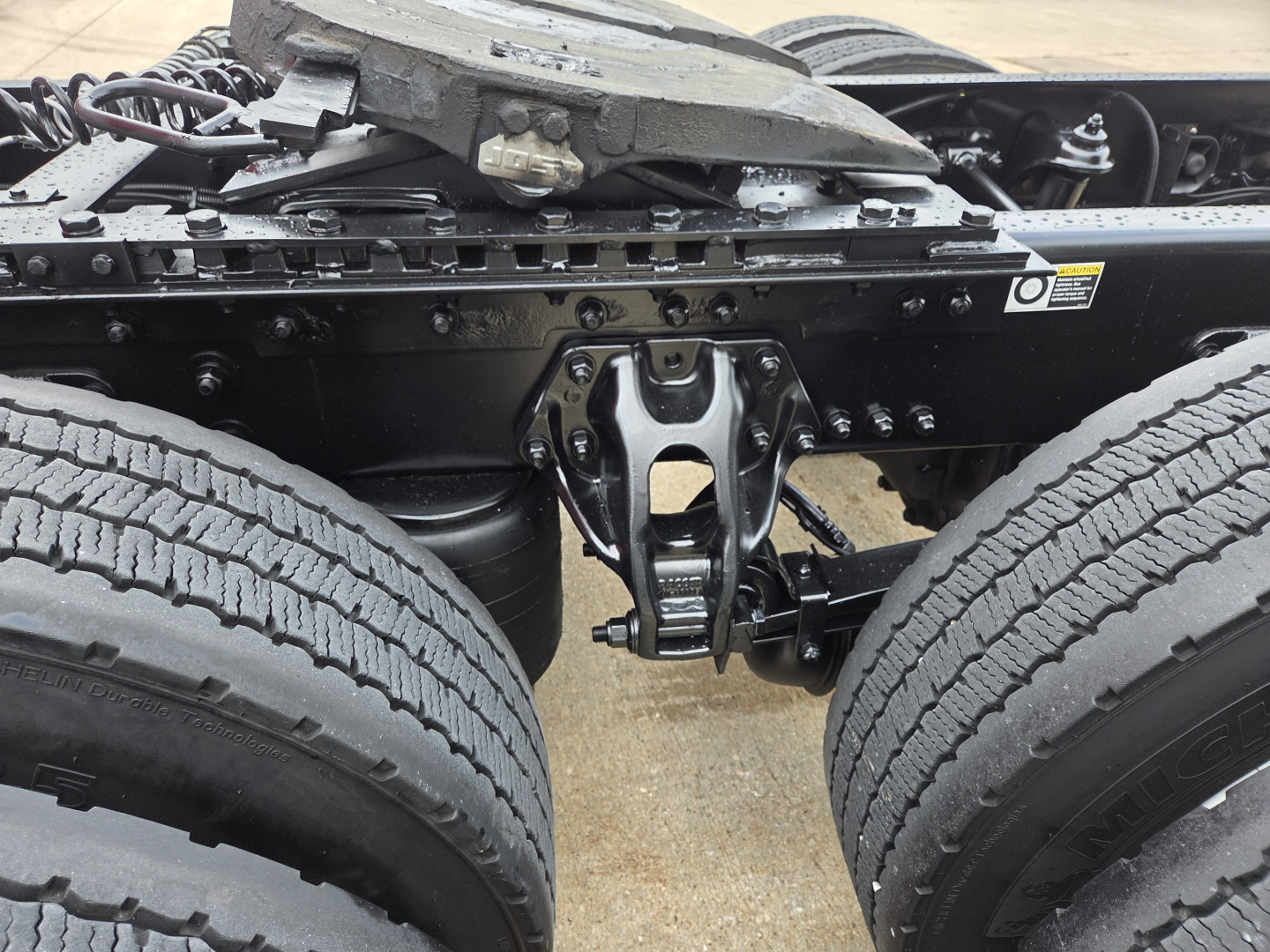 Kenworth truck rear undercarriage showing dual rear axles and suspension components in a close-up view.
