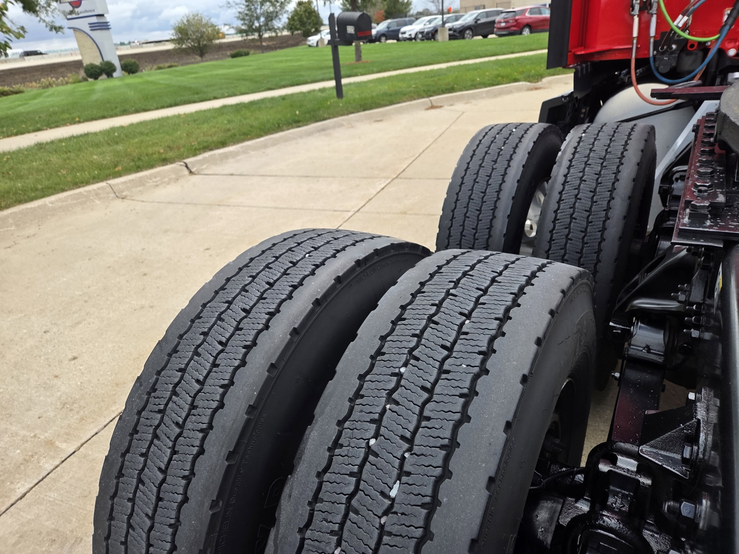 Kenworth T680 wheel area showing dual rear axles and tires with visible tread and suspension components.