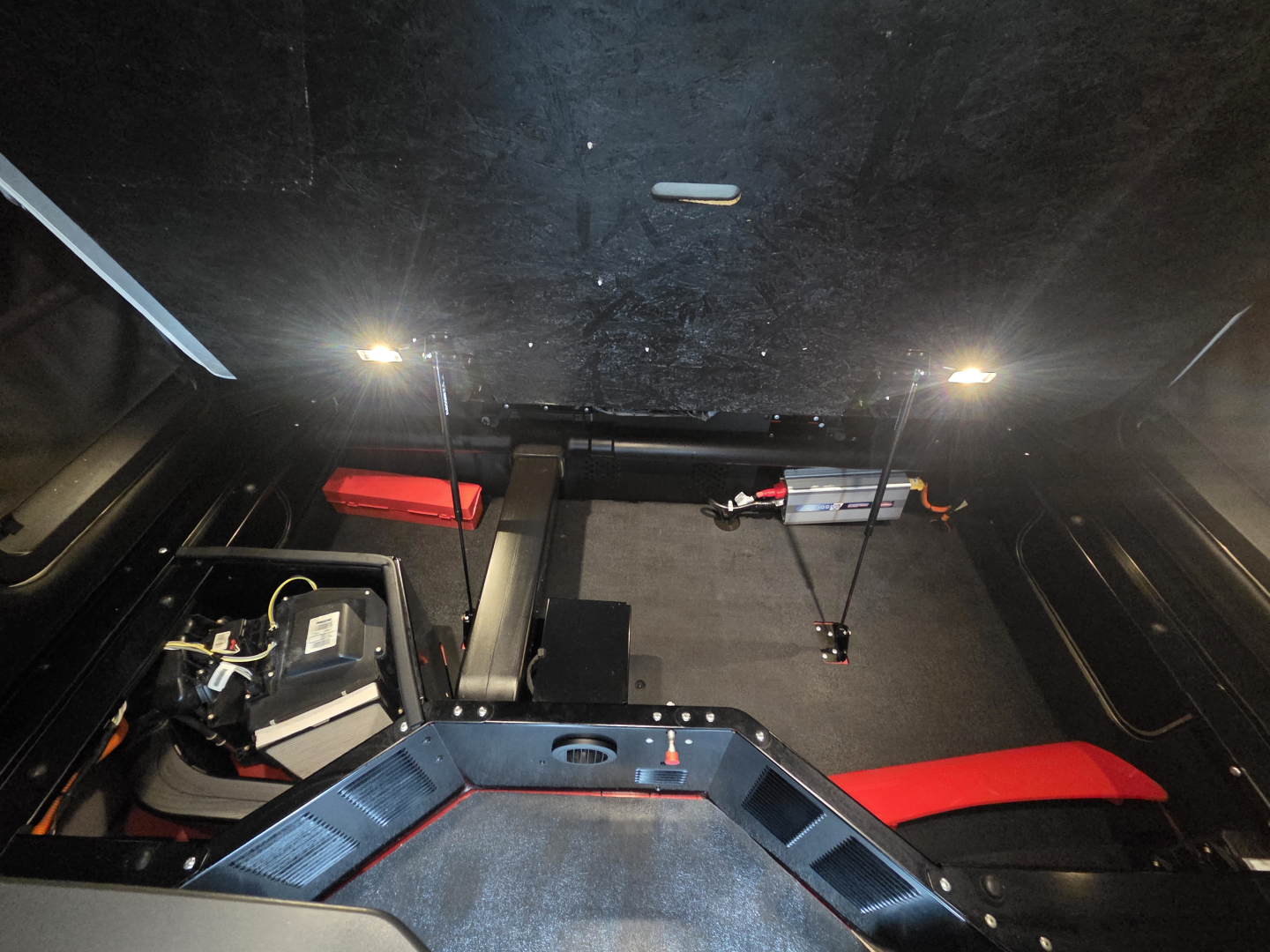 Kenworth T680 cab interior showing sleeper area and control panel with wiring; seating and overhead lighting visible.