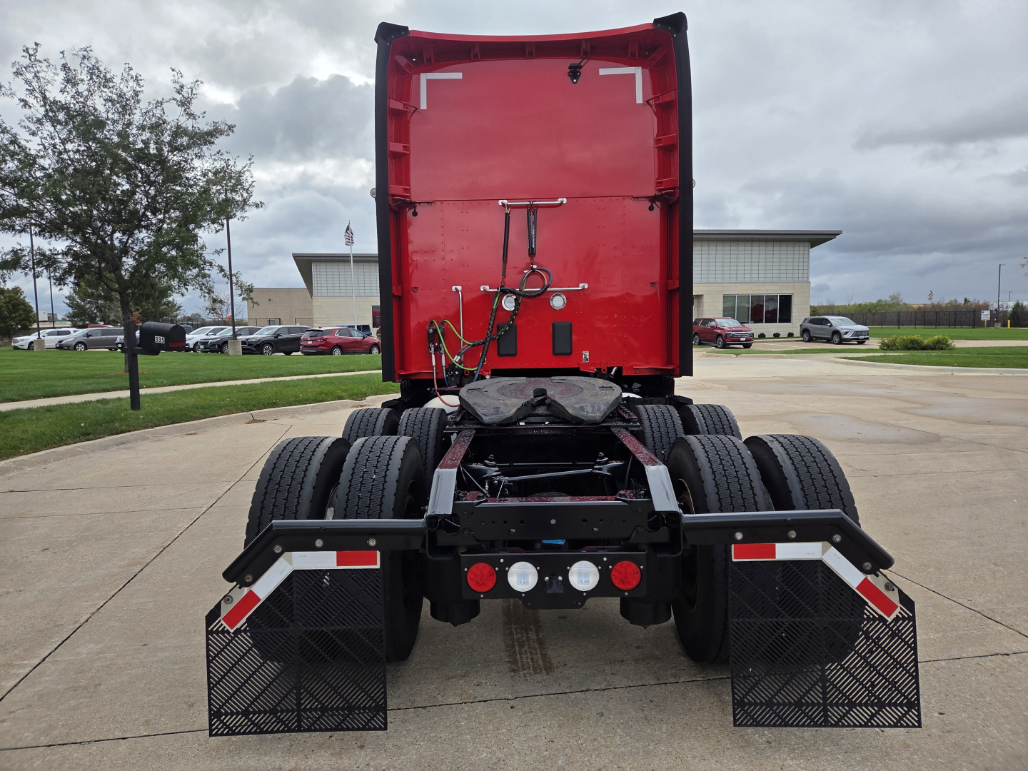 Kenworth T680 rear view showing fifth wheel, chassis, dual rear axles, mud flaps, and hydraulic lines.