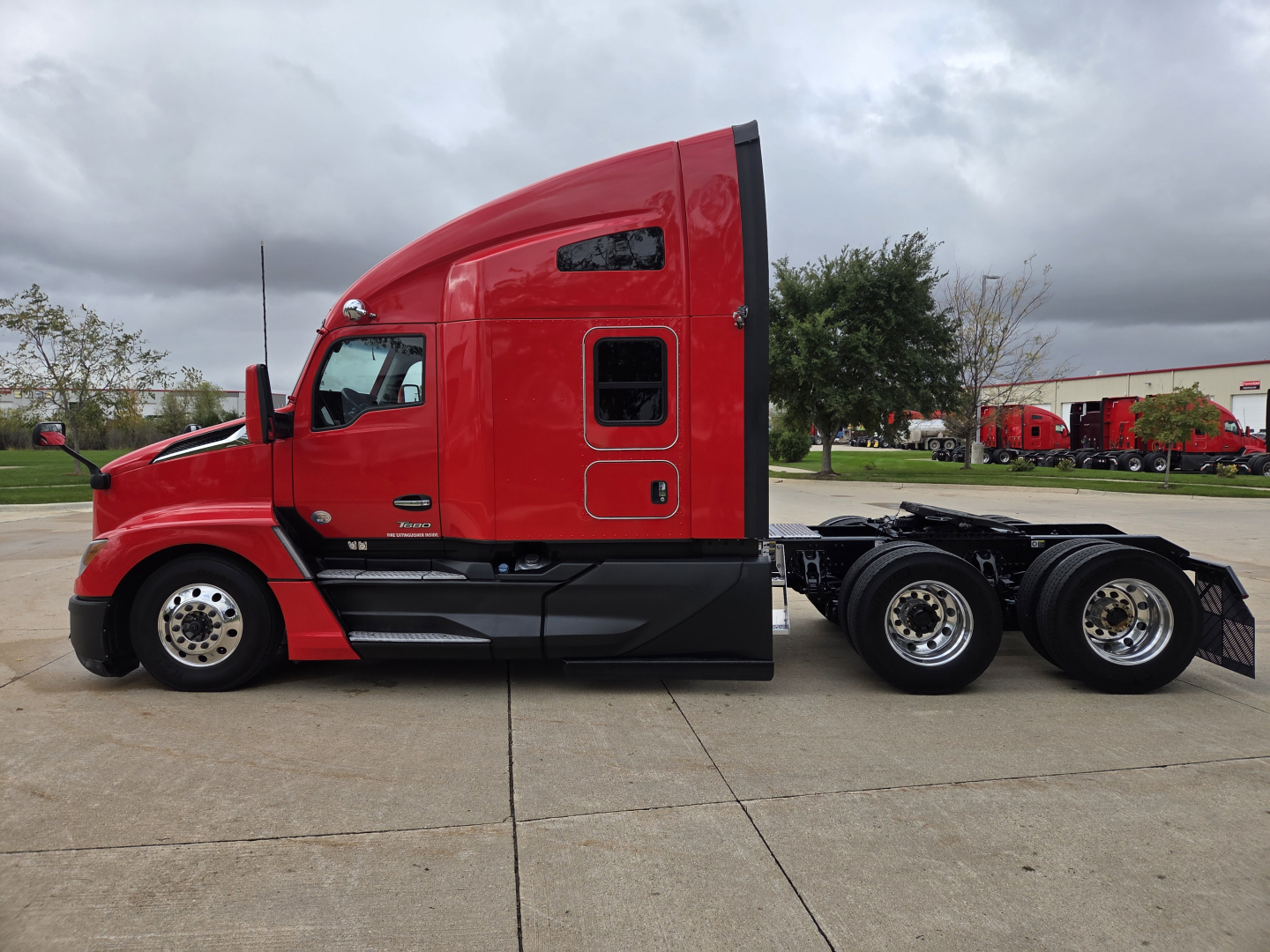 Kenworth T680 semi-truck side profile in red cab with sleeper, black lower panels, and dual rear axle showing aftermarket wheels.