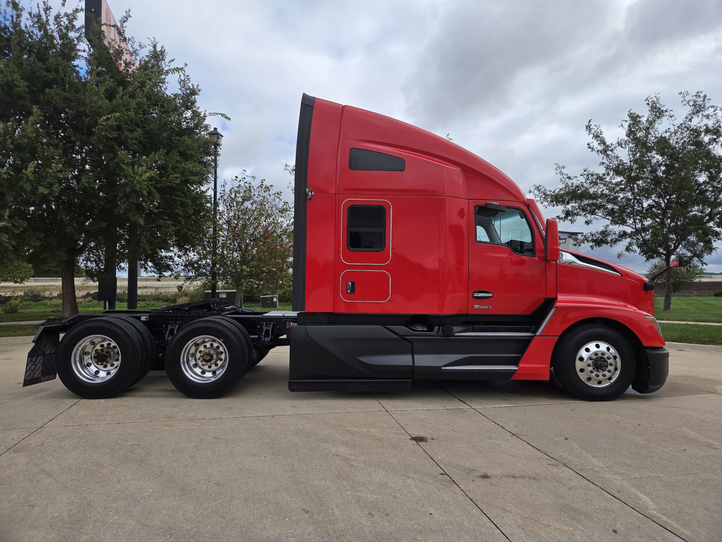 Kenworth T680 front cab and long red tractor with sleeper, side profile showing wheels and chassis.