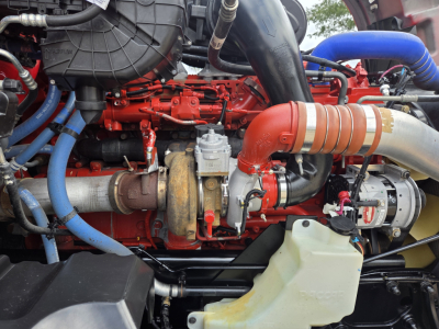 Kenworth T680 engine bay with red engine block, blue hoses, and large red turbocharger pipe visible.