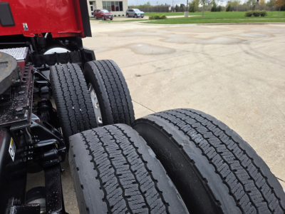 Truck rear wheels and frame of a 2023 Kenworth T680 tractor show dual rear axles and Detroit/ Cummins drive tires. Includes visible dual tires and hitch area.