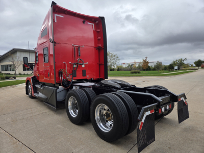 Kenworth T680 sleeper tractor rear cab with red paint and dual rear axles visible.