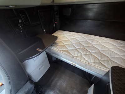 Kenworth T680 sleeper cab interior with a bed mattress and cabinet area visible.