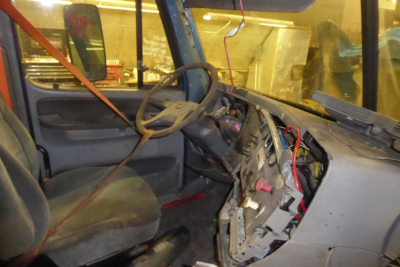 Dashboard and steering wheel area of a Freightliner CL112 cab interior with exposed wiring and dashboard components.