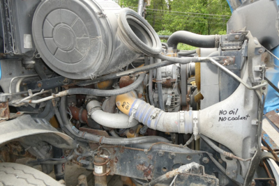 Freightliner CL112 engine bay showing air intake, hoses, and radiator hose; handwritten note on radiator shroud: No air no coolant.