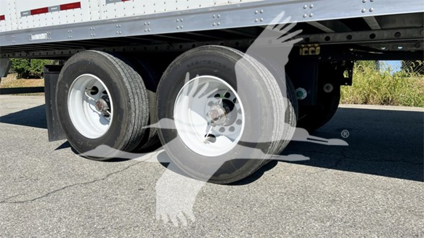 Dual rear axles with tires on Fruehauf plate trailer undercarriage showing wheel hubs and suspension.