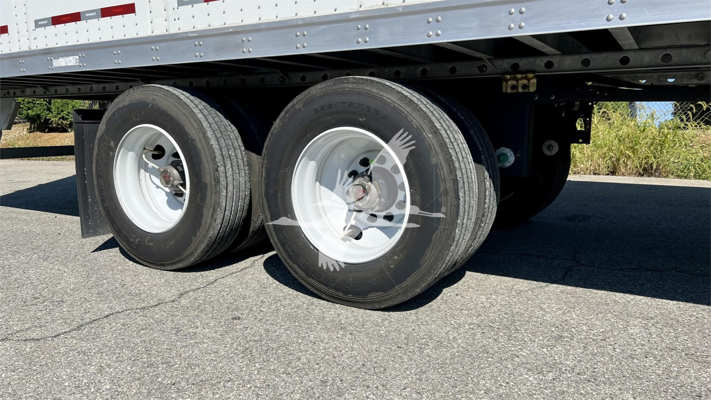 Dual rear trailer wheels and suspension under Fruehauf box trailer showing tires, rims, and frame.