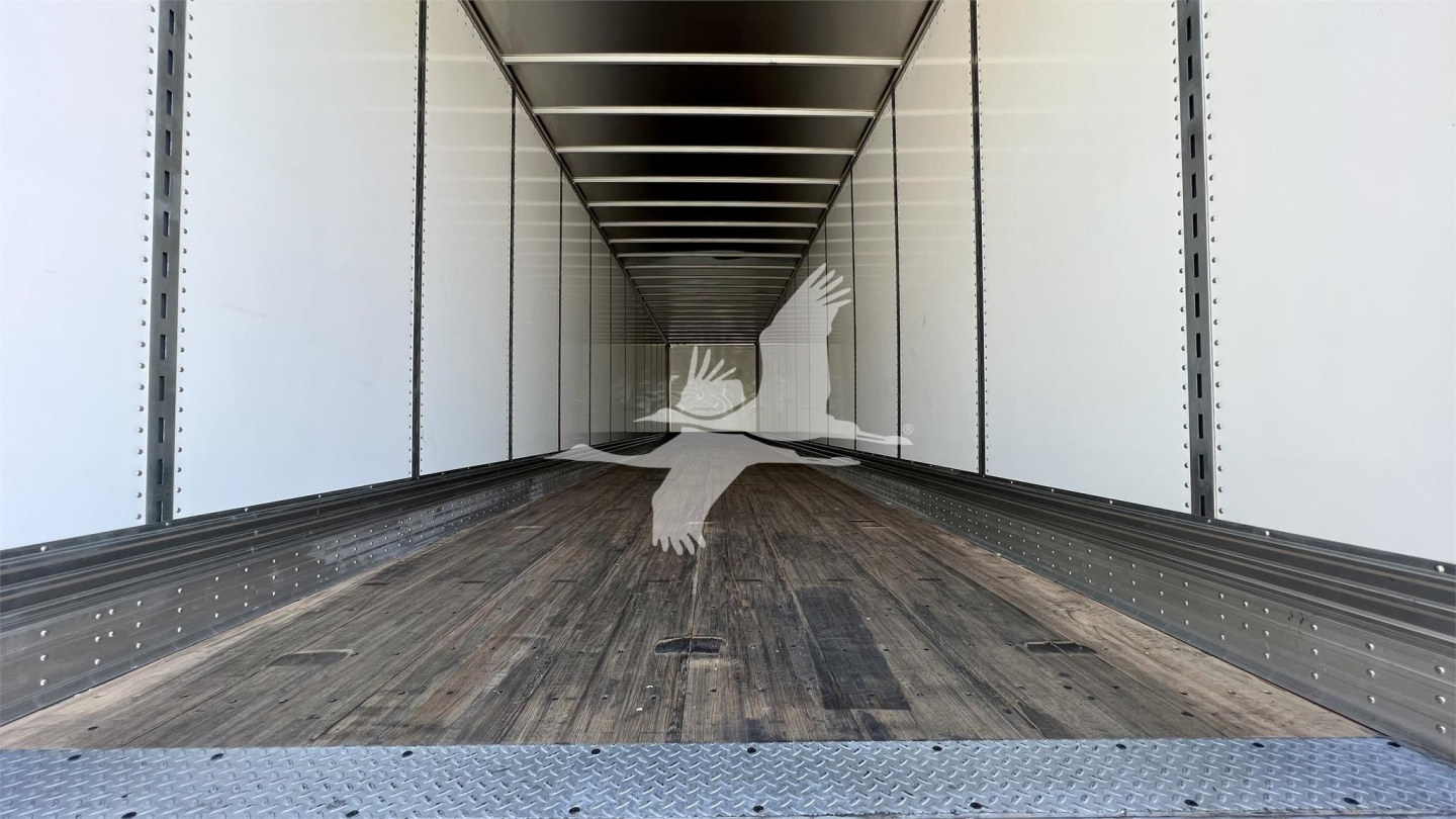 Interior of a Fruehauf van trailer cargo area with wooden floor, white side walls, steel ribs, and rear access at the far end.