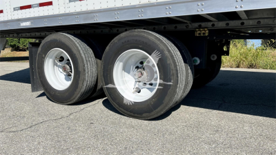 Dual rear trailer wheels and suspension under Fruehauf box trailer showing tires, rims, and frame.